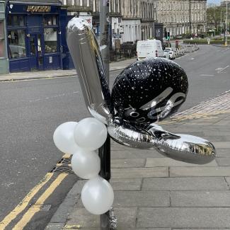 Birthday balloons tied to a lamppost.