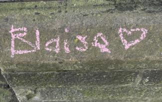 The name 'Blaise' with a heart symbol, written in pink chalk on a wall.