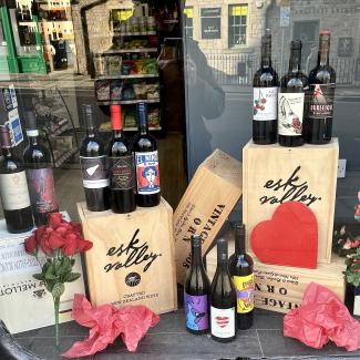 Bottles of wine with heart decorations in a shop window.