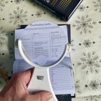 Magnifying glass held over a table of proofreading marks.